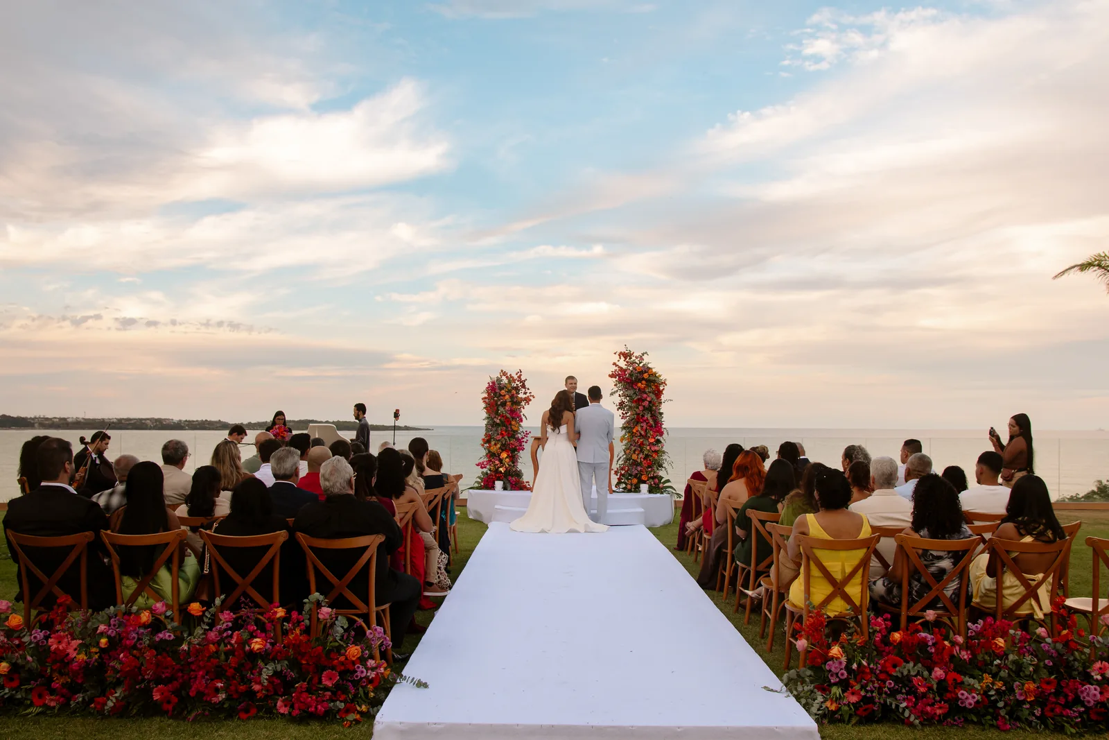 Cerimônia ao fim da tarde no Mirante Singular, com o casal diante do mar e um amplo céu